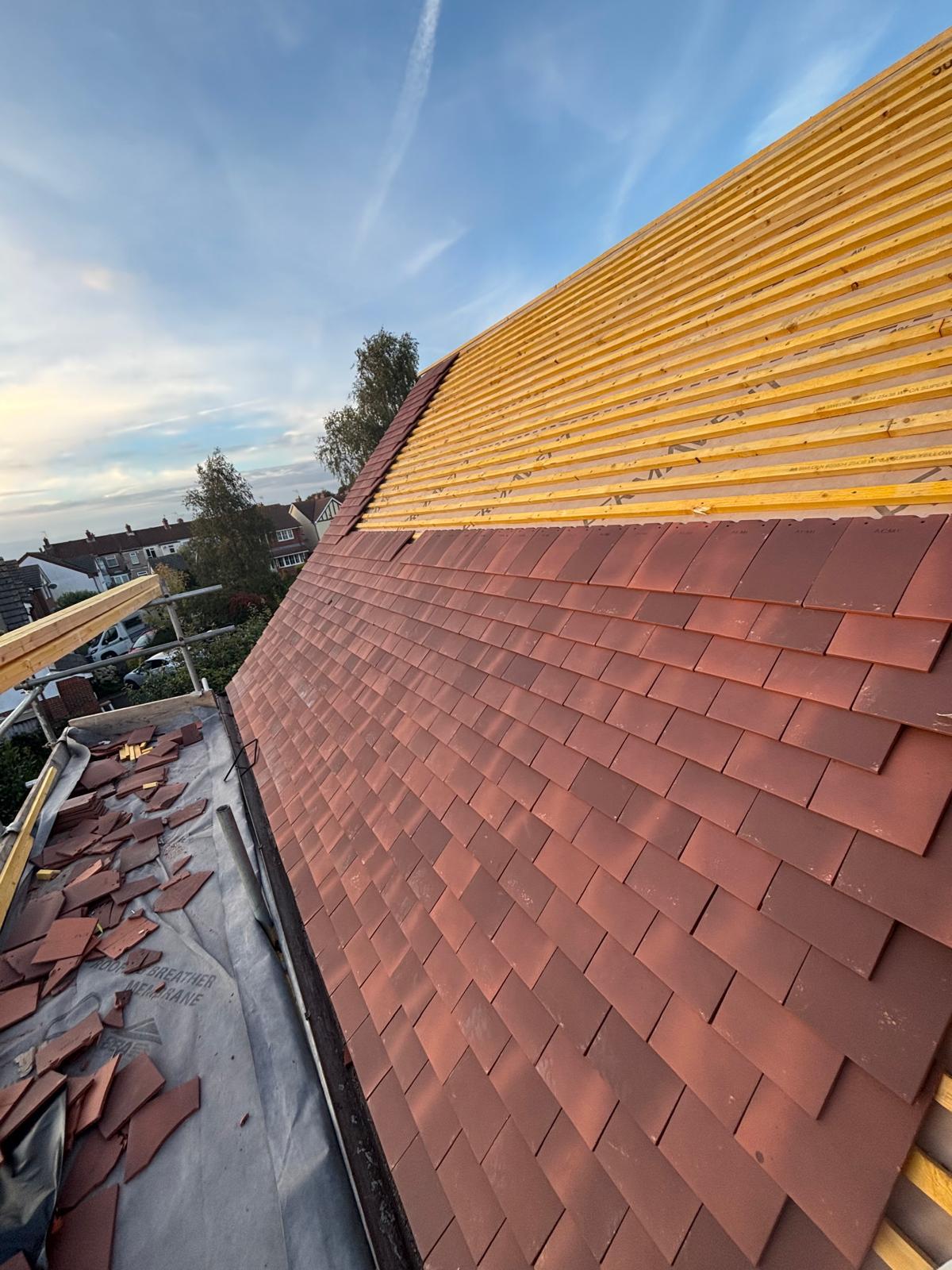Clay plain tile roof mid-installation over new counter-battens and membrane