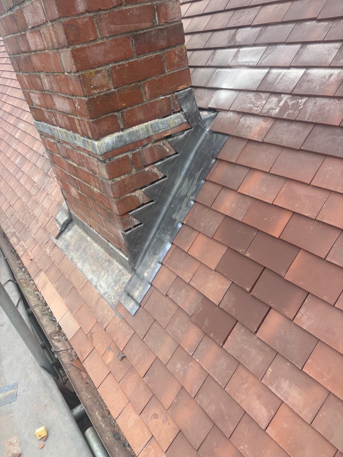 Fresh lead flashing and soakers around a brick chimney on a new clay tile roof