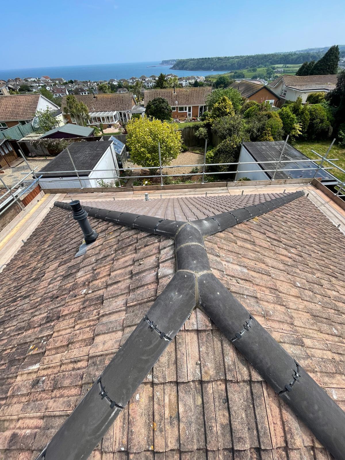 Ridge and hip leadwork with sea-view backdrop after full re-roof
